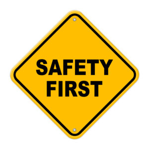 Yellow safety first road sign with rivets on a white background