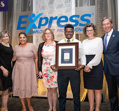 Group of Express employees in an Express location holding a plaque